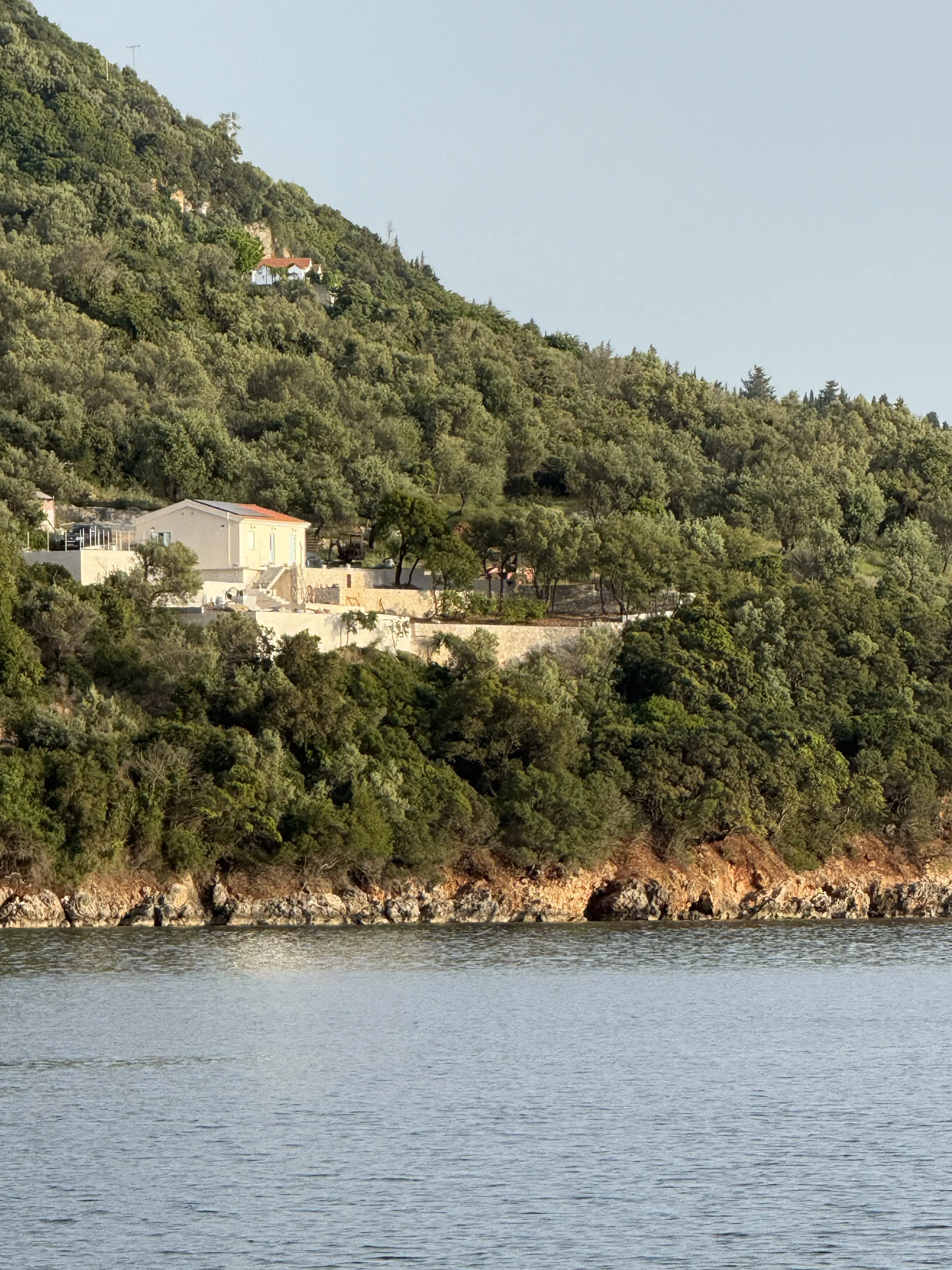 The house on a wooded hillside above the sea in northern Ithaki, seen from the water